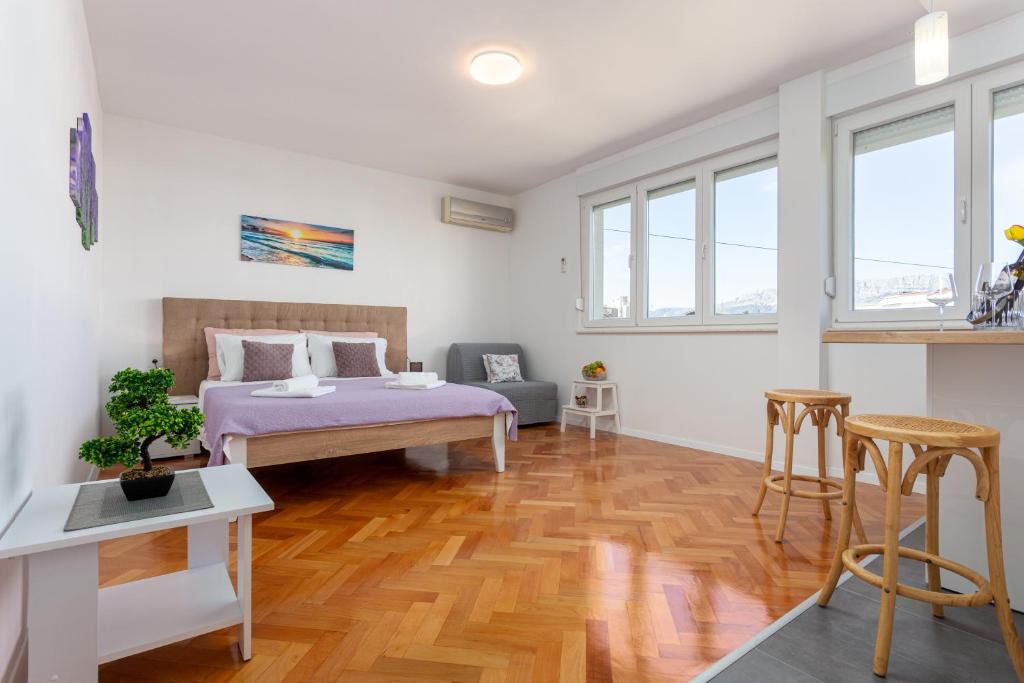 een slaapkamer met een bed en houten vloeren en ramen bij Botan Apartment in Split