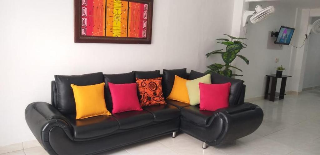 Un sofá de cuero negro con almohadas coloridas. en Hostal Girasoles Tolu en Tolú