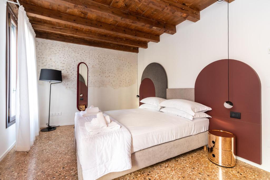 Palazzo Miracoli Apartments في البندقية: غرفة نوم بسرير كبير وسقف خشبي