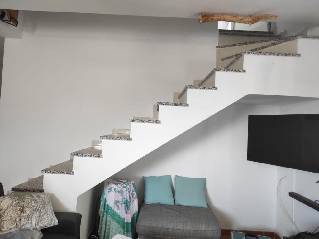 a living room with a staircase with a couch and a tv at Laylas Beach Art House in Cotillo