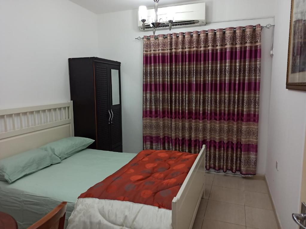 a bedroom with a bed and a curtain at Furnished Apartment in Sharjah