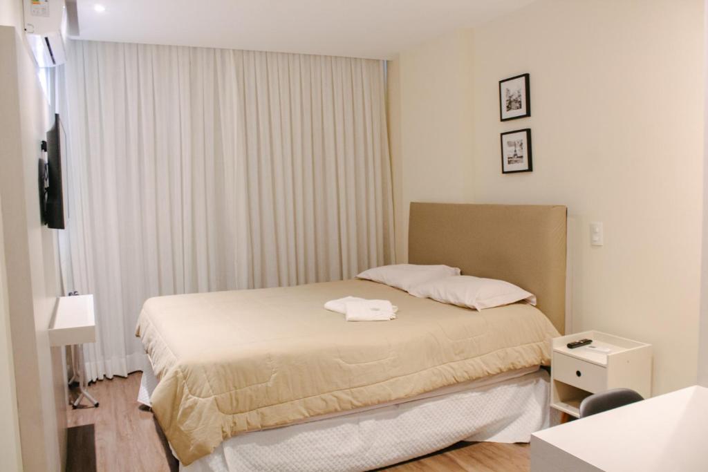 Apart-hotel TrueAmérica في كامبوس دوس جويتاكازيس: غرفة نوم صغيرة بها سرير ونافذة