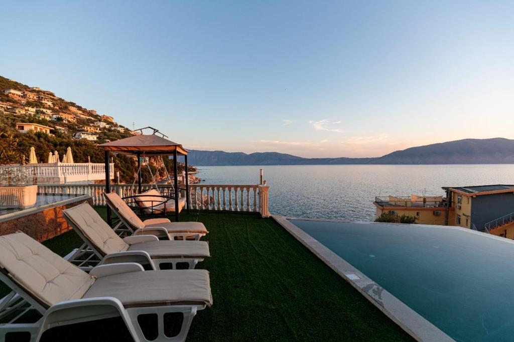 a group of lounge chairs sitting on a deck next to the water at Hakuna Matata Residence & Apartments in Vlorë