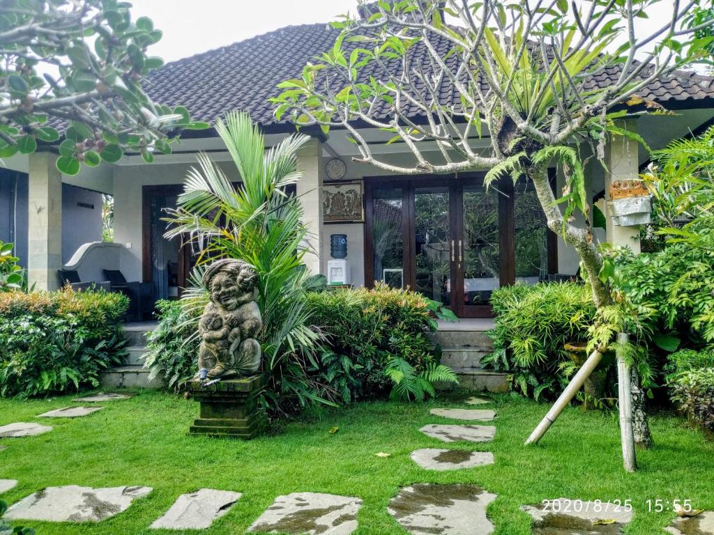 a garden in front of a house with a statue at Putu's Paradise Guesthouse in Ubud