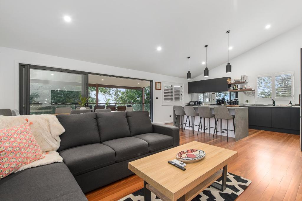 sala de estar y cocina con sofá y mesa en 24 Hibiscus Crescent Port Macquarie en Port Macquarie