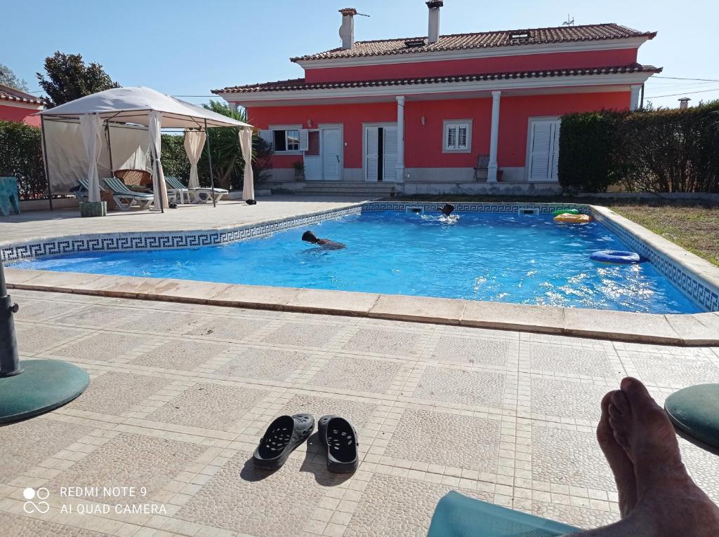 un par de zapatos sentados en una piscina con una casa en Barrio Latino, en Samora Correia