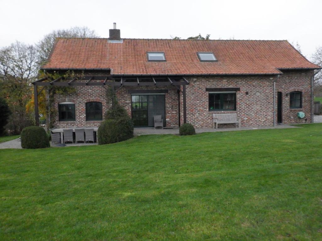 ein Backsteinhaus mit grünem Rasen davor in der Unterkunft Vakantiehuis Montezicht in de groene heuvels van Dranouter in Heuvelland