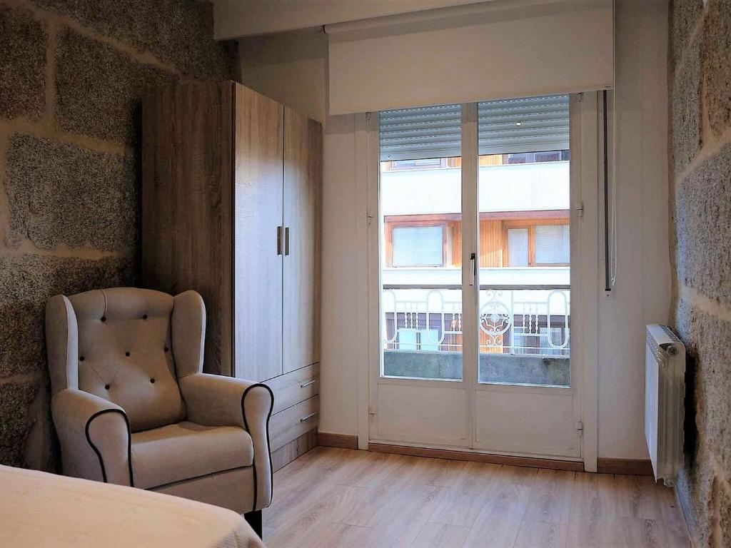 1 dormitorio con silla y puerta corredera de cristal en Beautiful Apartment in Ourense overlooking the City, en Ourense