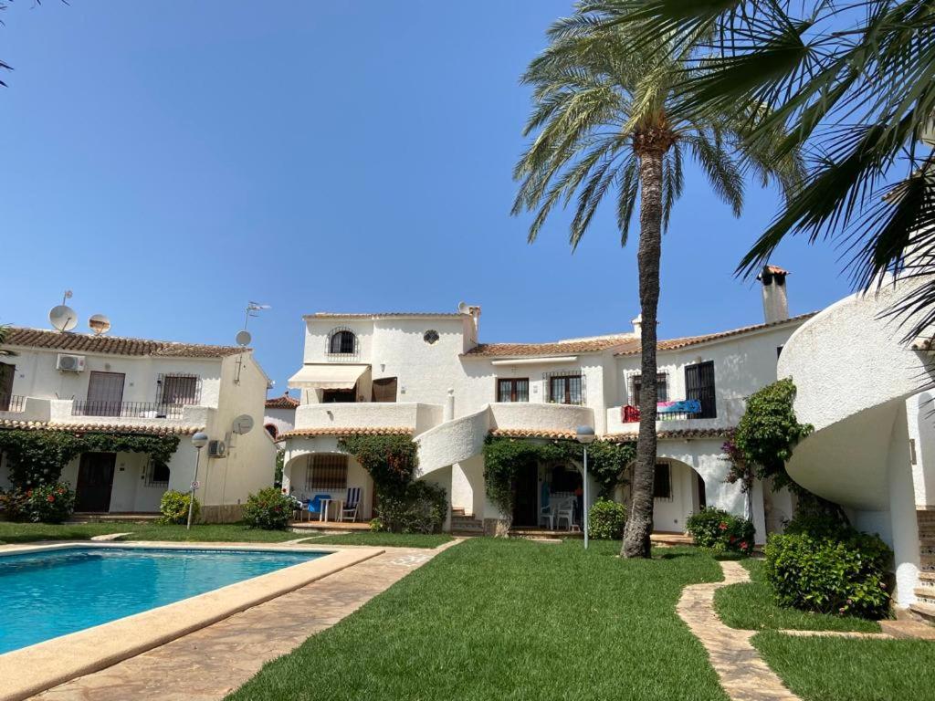 ein großes Haus mit einem Pool und einer Palme in der Unterkunft Apartamento Urb Oasis Park II Denia, las Marinas in Denia