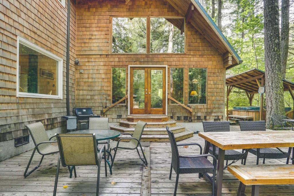 a patio with tables and chairs in front of a house at River Dance Retreat - Meredith Lodging in Welches