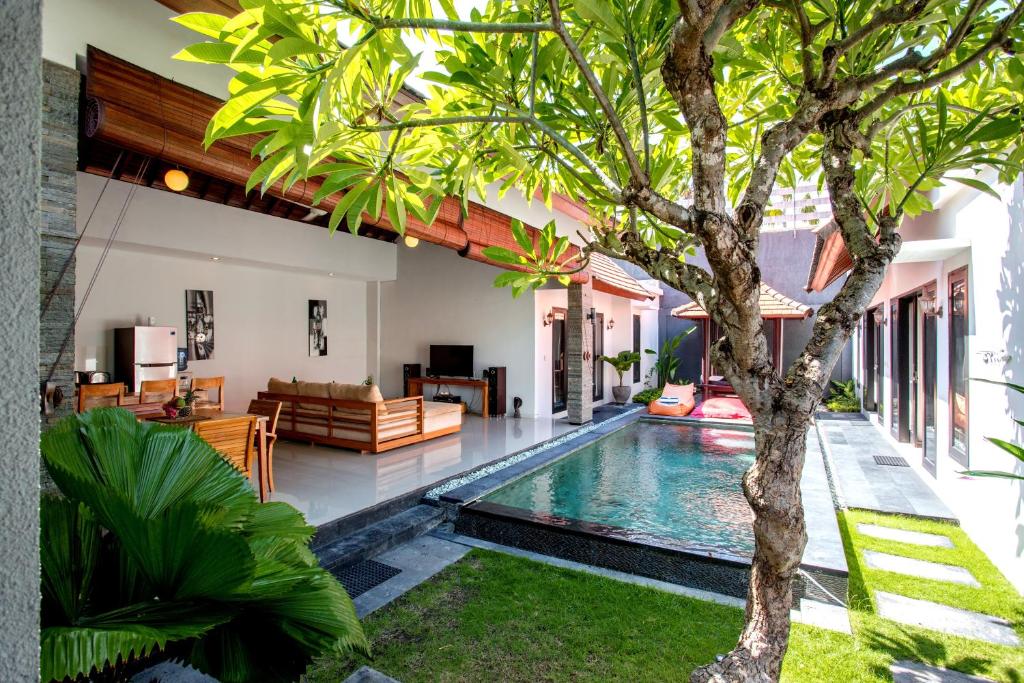 a swimming pool in a villa with a tree at Villa Joylen Seminyak Bali in Seminyak