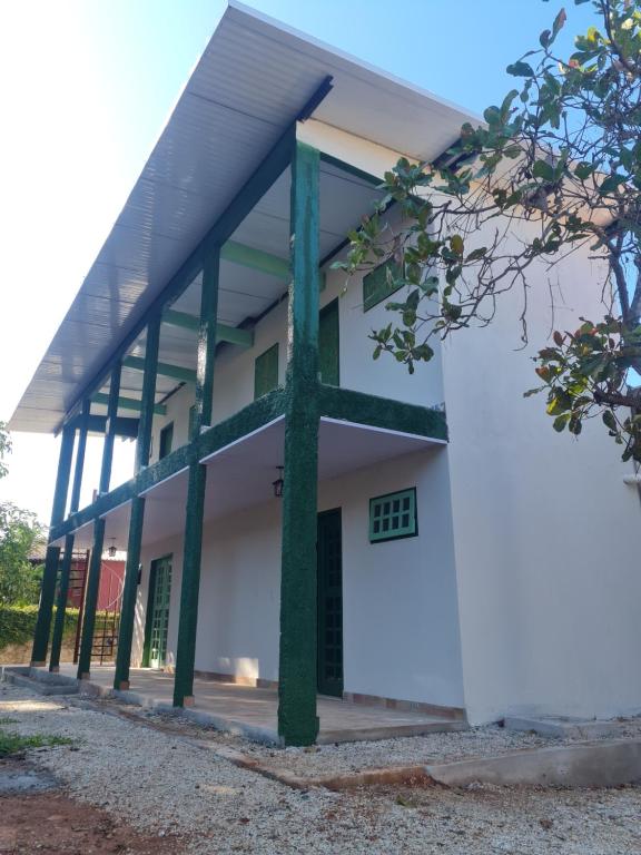 un edificio blanco con pilares verdes en Suítes Pirenópolis, en Pirenópolis
