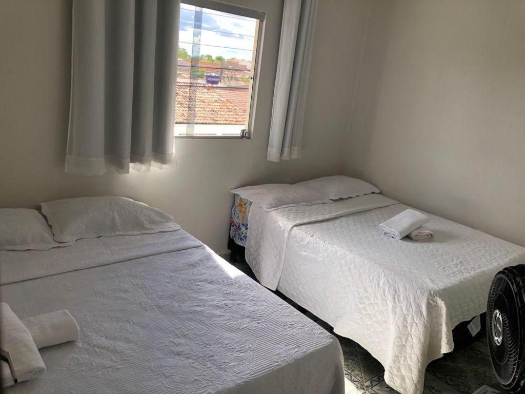 two beds in a small room with a window at Casa Família Sena in Piranhas