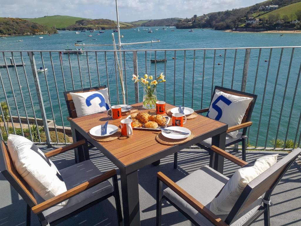 a wooden table on a balcony with a view of the water at 35 The Salcombe in Salcombe