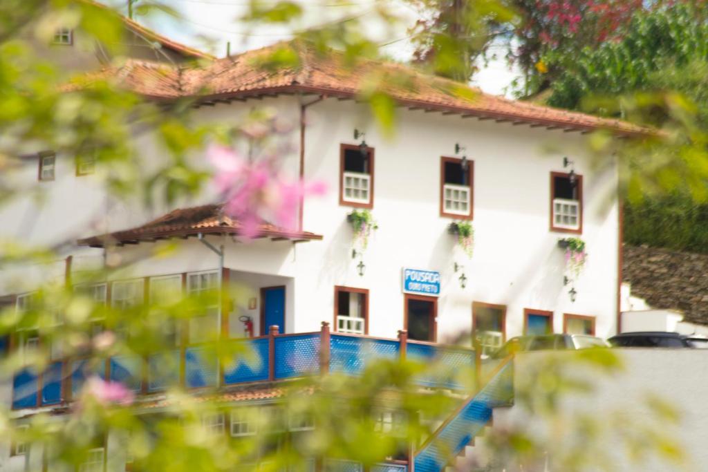 una casa blanca con una valla azul delante de ella en Pousada Ouro Preto en Ouro Preto