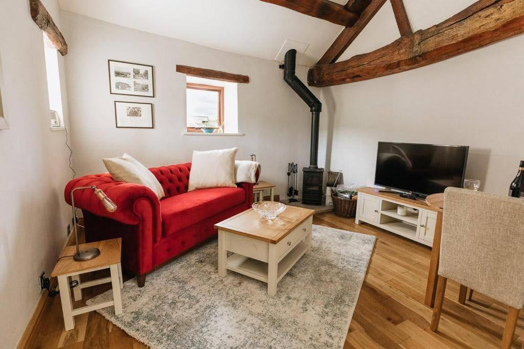 a living room with a red couch and a tv at GABLE COTTAGE - One Bed Cottage Close to Holmfirth and the Peak District in Hepworth