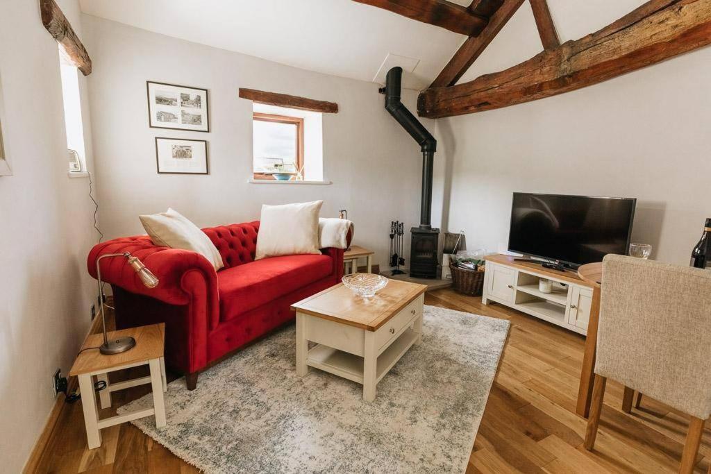 ein Wohnzimmer mit einem roten Sofa und einem Fernseher in der Unterkunft GABLE COTTAGE - One Bed Cottage Close to Holmfirth and the Peak District in Hepworth