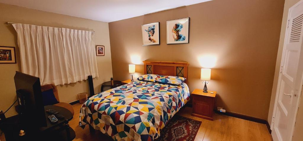a bedroom with a bed with a colorful comforter and two lamps at Miraflores Dpto 2 dorm. espaciosos 4 huéspedes 90m2 in Lima