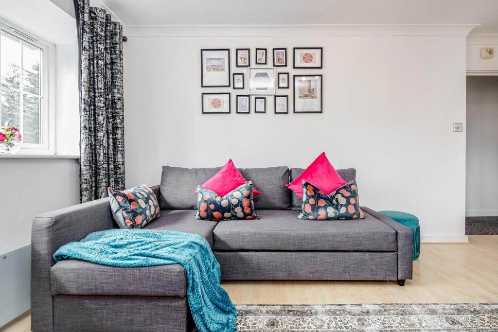 a living room with a gray couch with pink pillows at Stunning 2-Bed Apt - Free Parking - Gated Hideaway - Watford Gen Hospital - Watford FC - Shopping - Atria in Watford