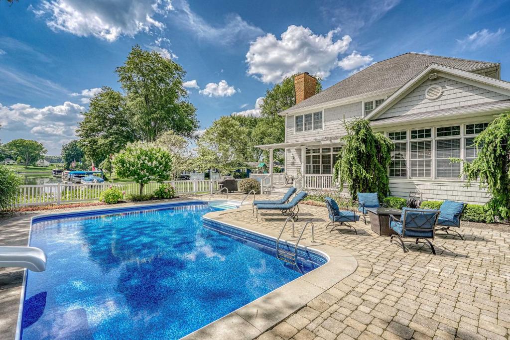 uma piscina com cadeiras e uma casa em Executive Home with Heated Pool on Lake Wawasee em Syracuse