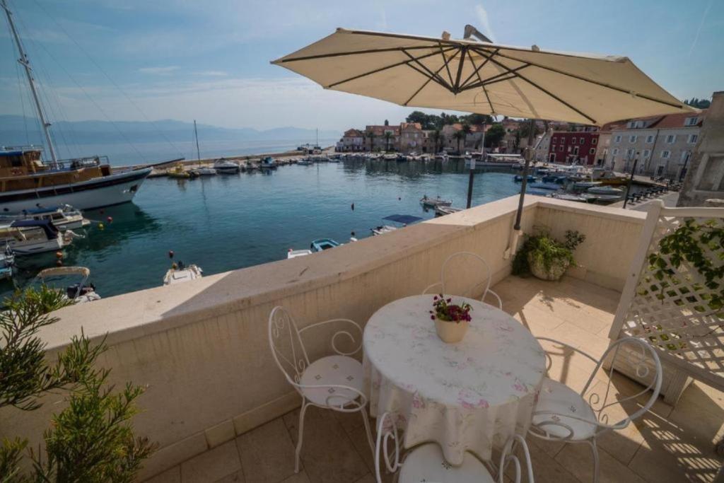 a table and chairs on a balcony with a view of a harbor at Apartments Ela - first row to the Sea in Sutivan