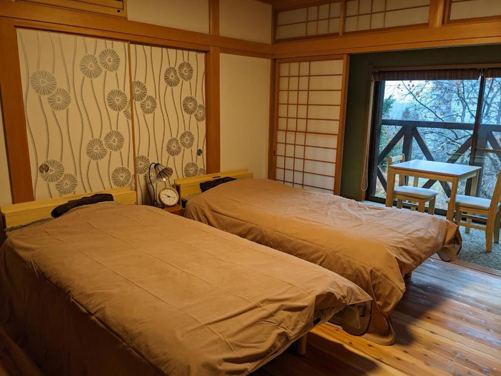 豊岡市にあるワンコと泊まるジャスミンクリークのベッド2台、テーブル、窓が備わる客室です。