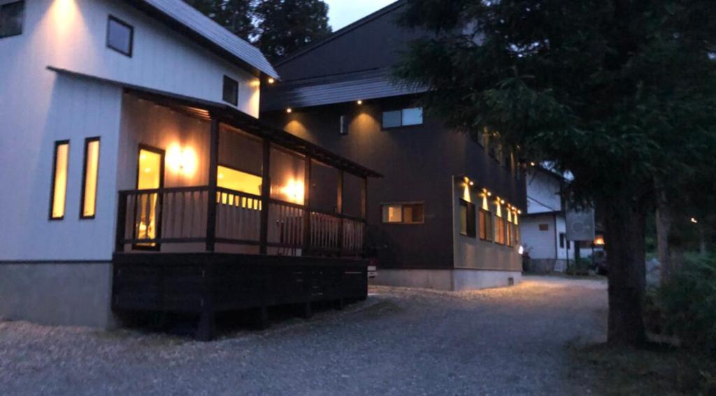Ski-in, Ski-out House in Hakuba في هاكوبا: منزل مع شرفة مع أضواء عليه في الليل