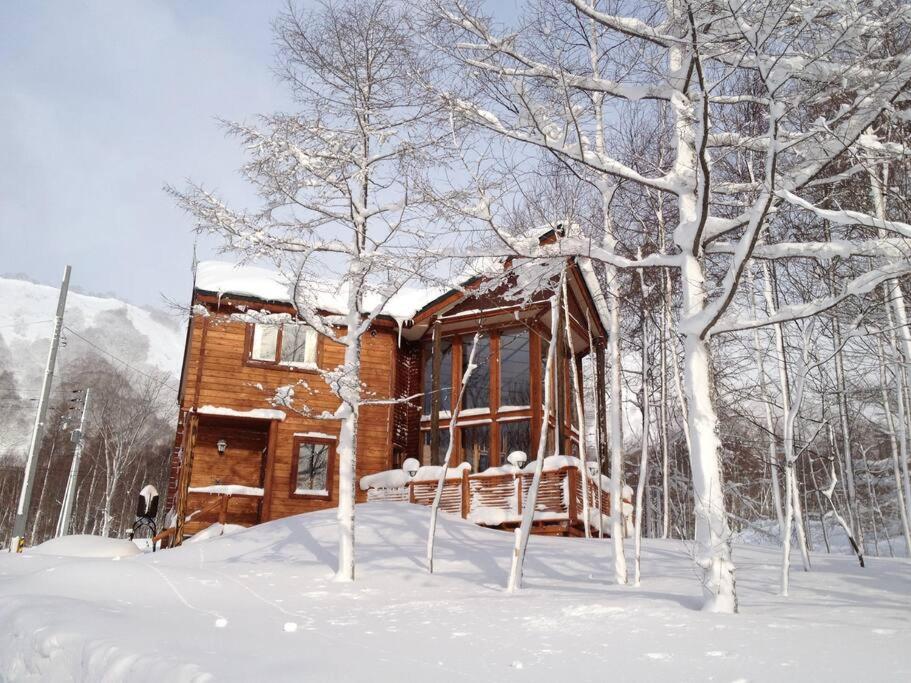 uma cabana de madeira na neve com árvores cobertas de neve em Midori House - walking distance to Rusutsu Resort em Rusutsu