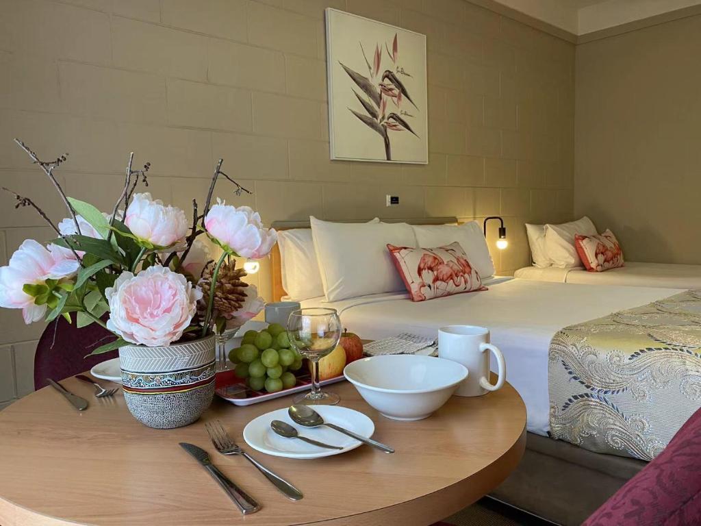 パークスにあるApollo Motel Parkesのベッド1台と花のテーブルが備わるお部屋