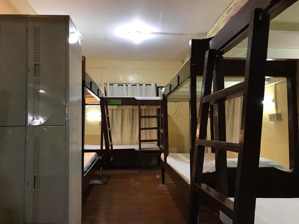a room with three bunk beds and a hallway at Austria's Guest House in El Nido