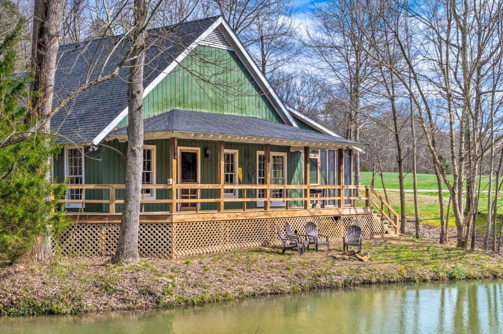 a large green house with two chairs in front of a pond at Bright Green Gables Cabin Hike, Swim and BBQ in Lewisburg