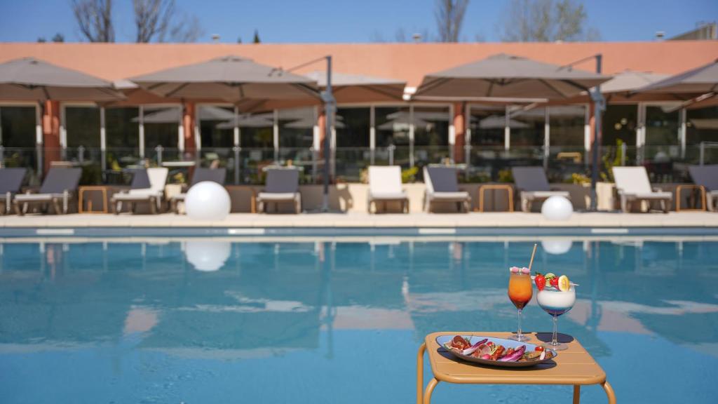 a tray of drinks on a table next to a swimming pool at Hôtel Mount Venturi - Aix-En-Provence Sainte-Victoire - Bar & Restaurant & Padel in Rousset