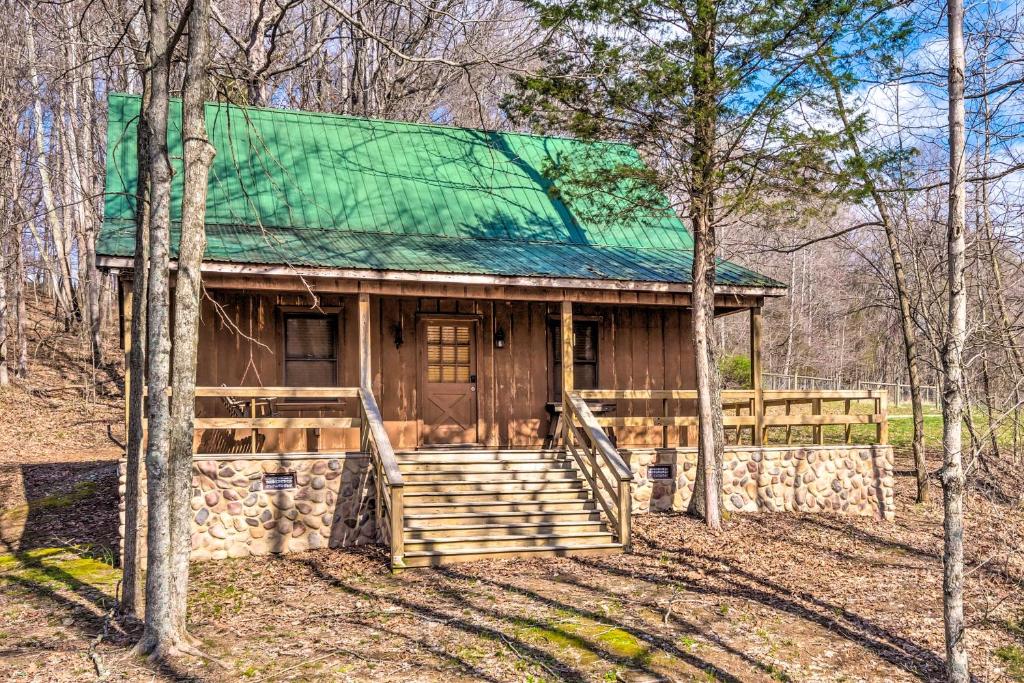 Cabaña de madera con techo verde en el bosque en Quaint Lakeside Cabin with Pond and Fire Pit!, en Lewisburg