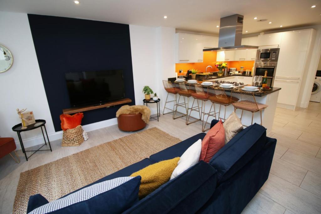 a living room with a blue couch and a kitchen at Bath Luxury City Centre 4 Bedroom Townhouse, Sleeps 8, Easy Parking, Private Courtyard Garden, by EMPOWER HOMES in Bath