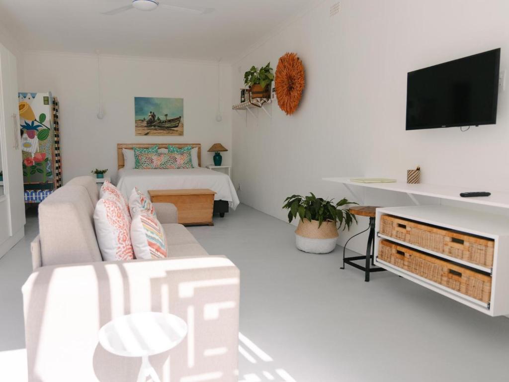 a white living room with a couch and a tv at McLeod's & Stuart's Cottage in Somerset West