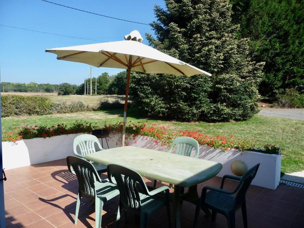 a table and chairs with an umbrella on a patio at Séjour à la campagne pour 6 in Commequiers