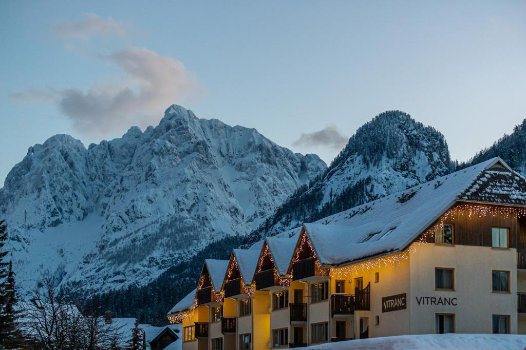 a hotel with snow covered mountains in the background at Vitranc Apartments in Kranjska Gora