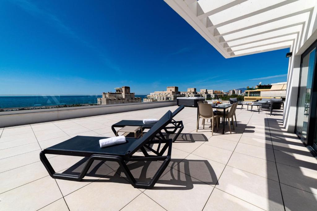 eine Terrasse mit Stühlen und Tischen auf dem Dach in der Unterkunft Aqua Apartments Bellamar, Marbella in Marbella