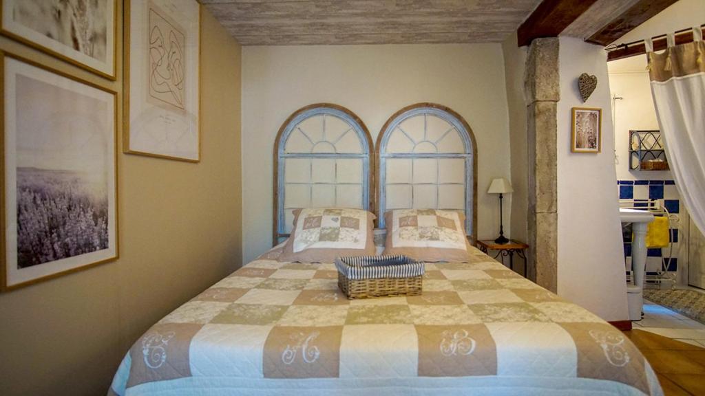 a bedroom with a large bed with two windows at Le Mas Fraissinet in Saint-Jean-de-Valériscle