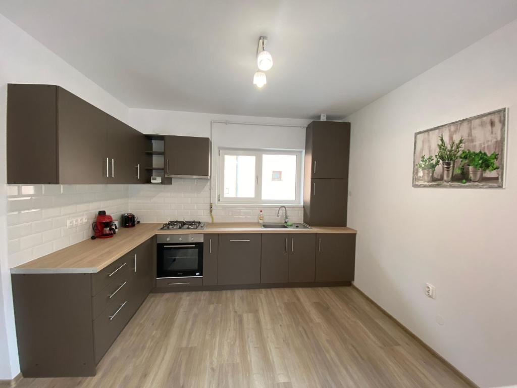a large kitchen with brown cabinets and a window at FENYŐ APARTMAN HOUSE II. in Odorheiu Secuiesc
