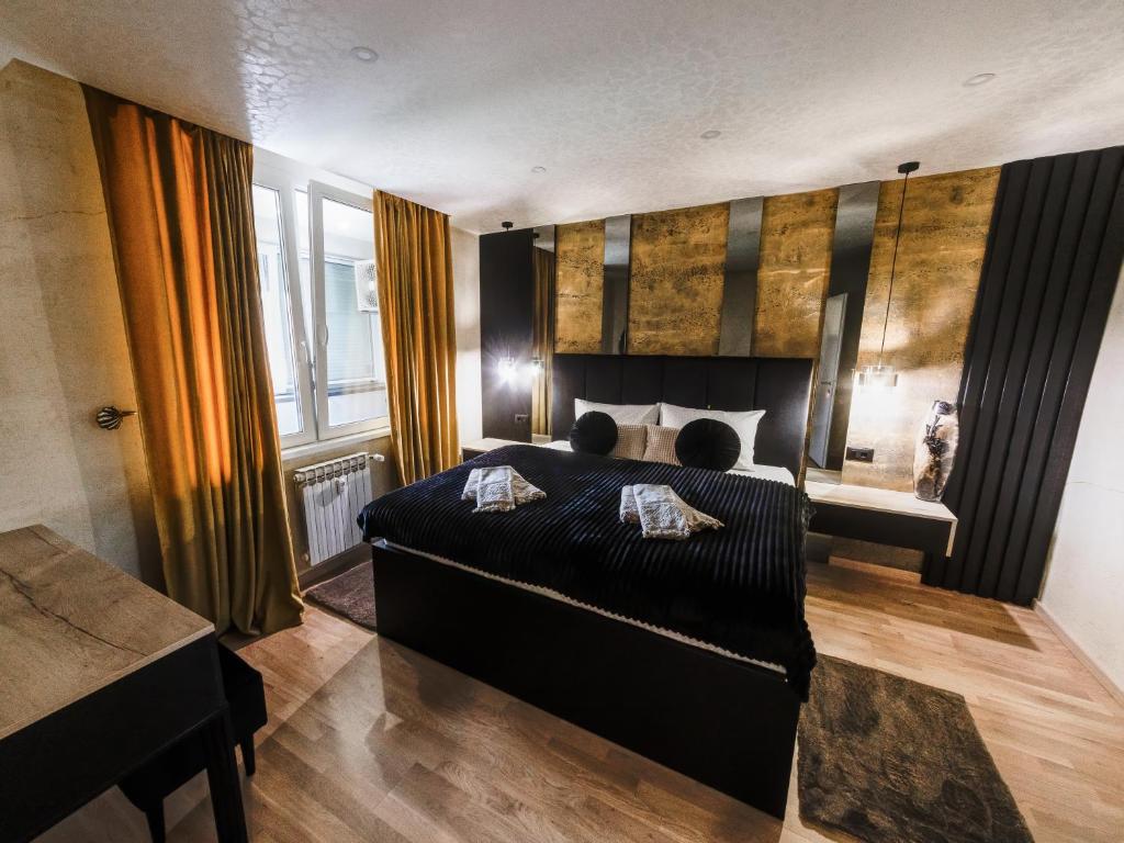 a bedroom with a black bed and a window at Apartman Stari Toranj II in Vukovar