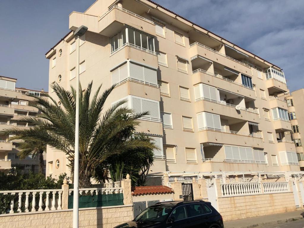 un bâtiment avec une voiture garée devant lui dans l'établissement Apartamentos Arenales del Sol, à Arenales del Sol