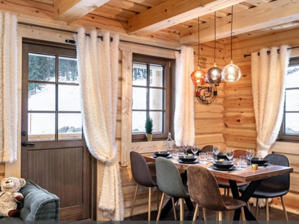une salle à manger avec une table, des chaises et des fenêtres dans l'établissement SUNWEB - Les Chalets de L'Ecrin, à La Joue du Loup