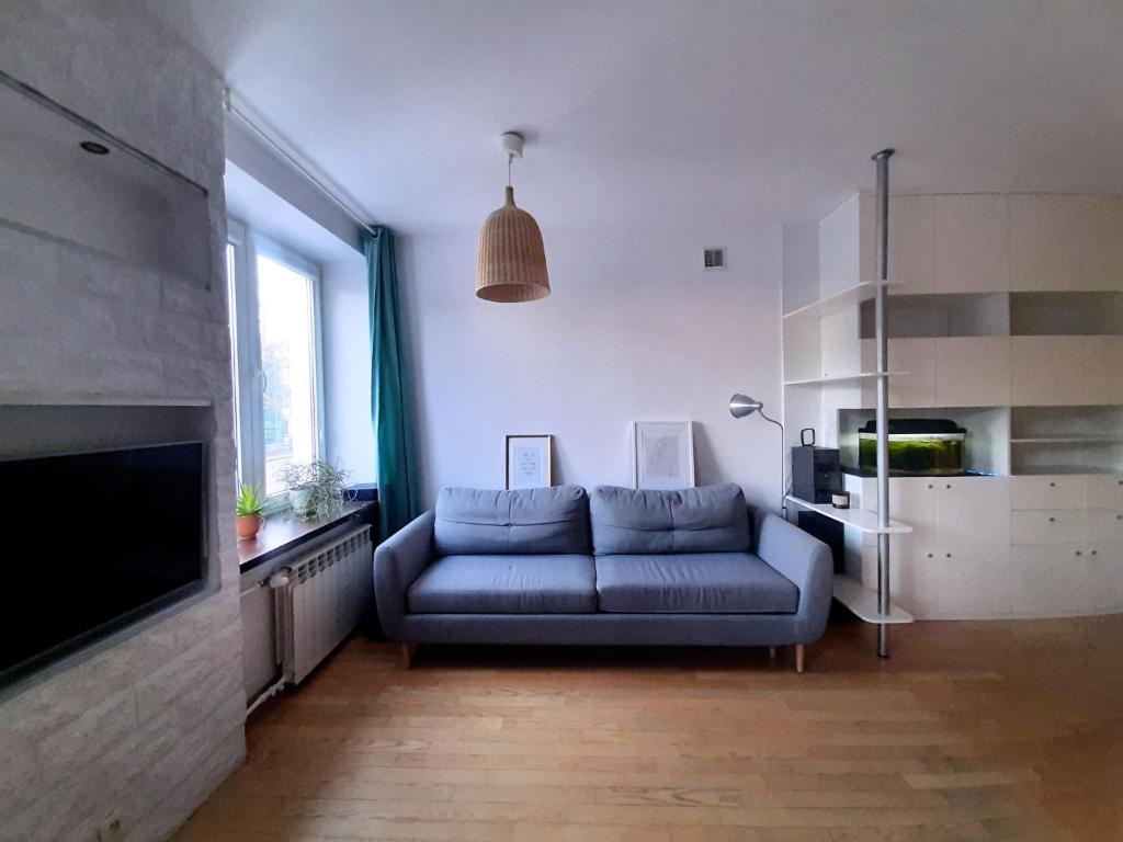 a living room with a blue couch and a tv at Apartament Rokosowska in Warsaw