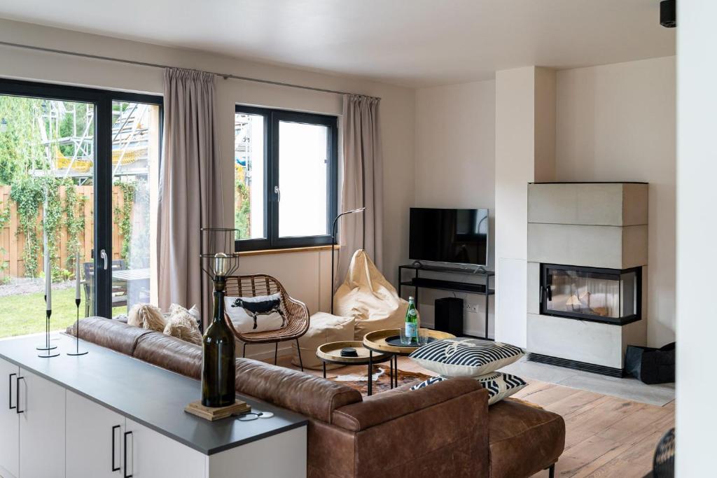 a living room with a couch and a table at Wellnesshaus "Strandflieder" mit Sauna, Kamin & Terrasse - ruhig & stilvoll in Zingst in Zingst