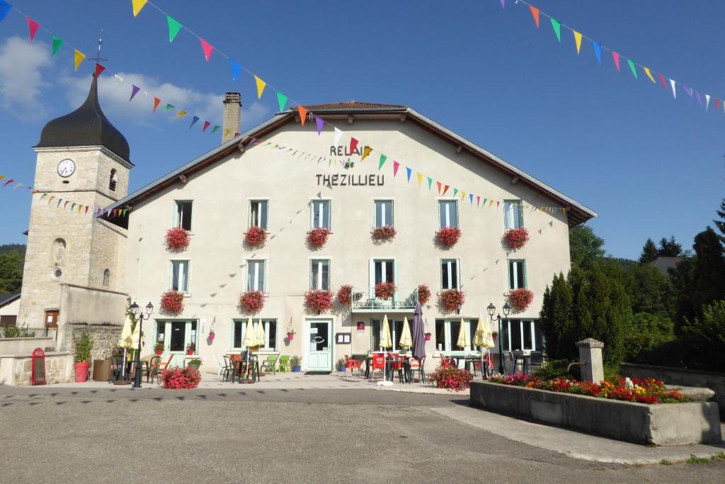 un gran edificio blanco con una torre de reloj en Logis Le Relais de Thézillieu en Thézillieu