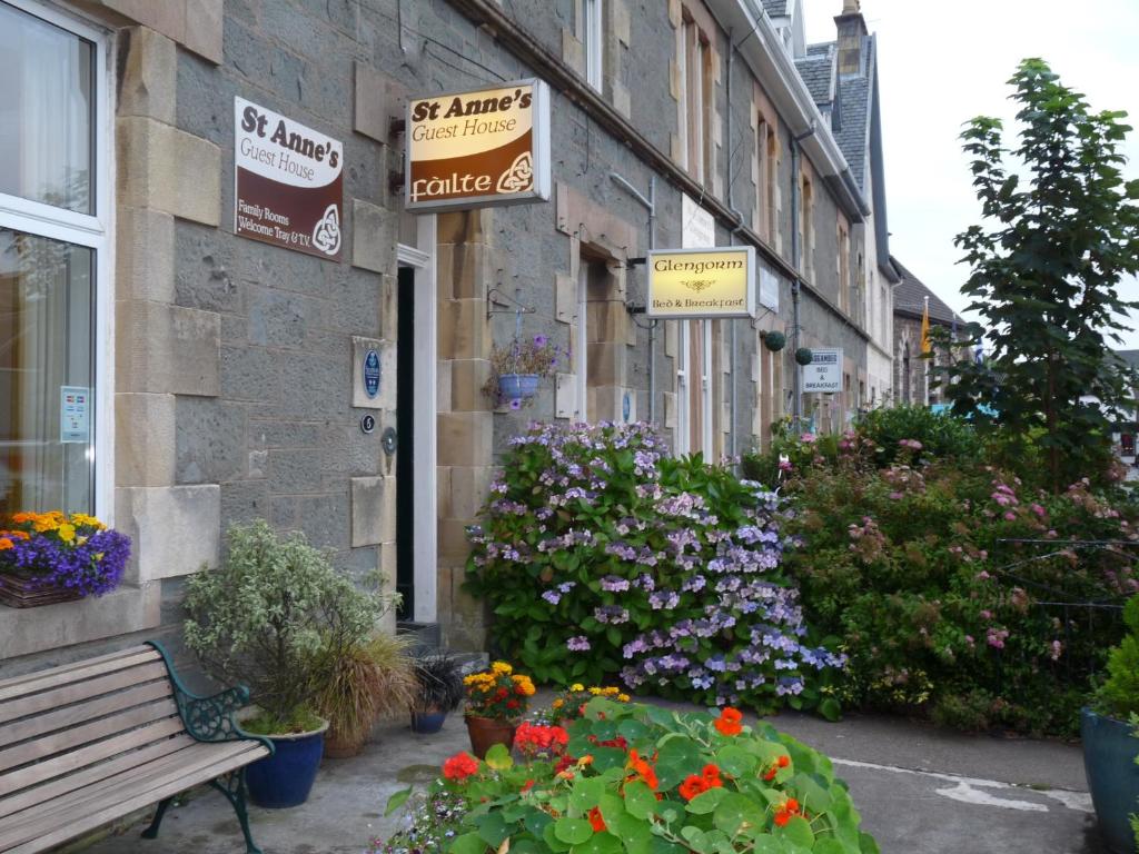 a building with flowers and a bench in front of it at Glengorm Guest House in Oban