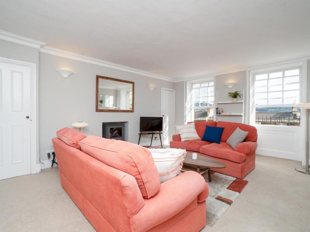 a living room with two orange couches and a television at Pass the Keys Lovely 1 bed flat with parking close to the centre in Bath