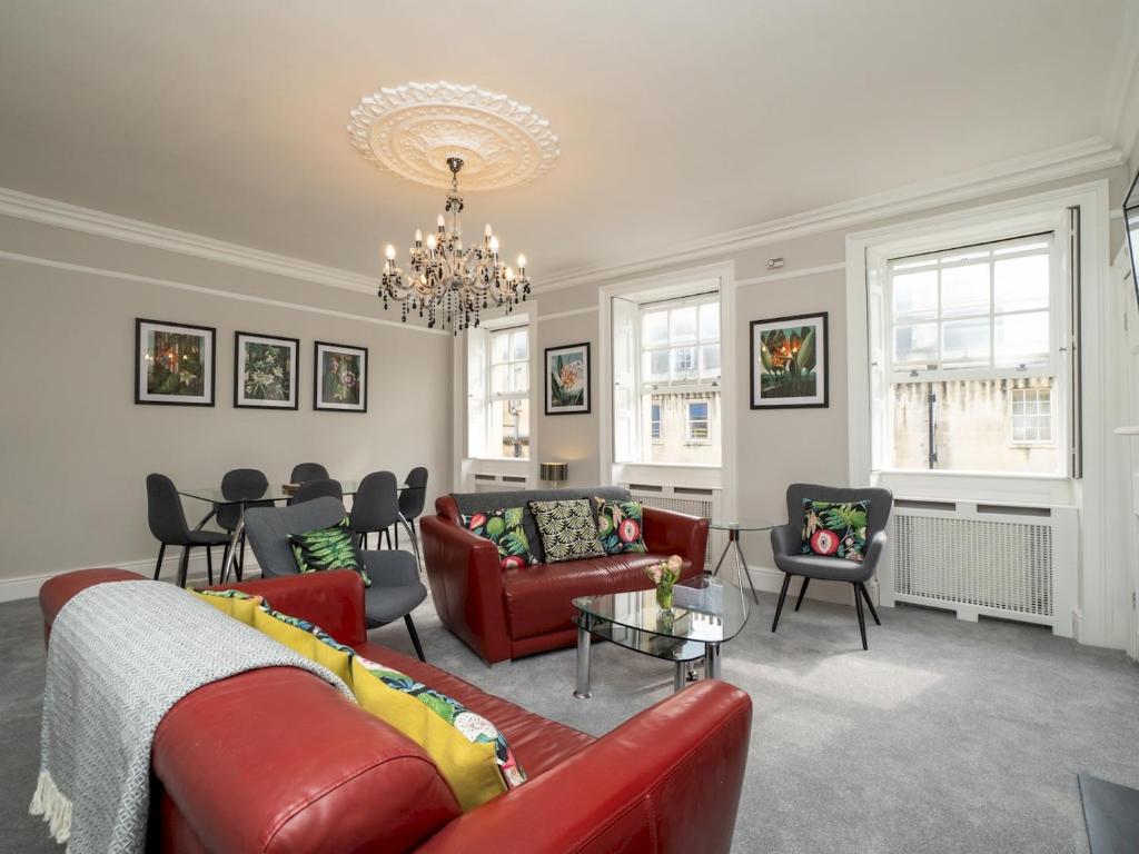 a living room with red furniture and a chandelier at Pass the Keys Spacious 3 bed apartment in prime central location in Bath