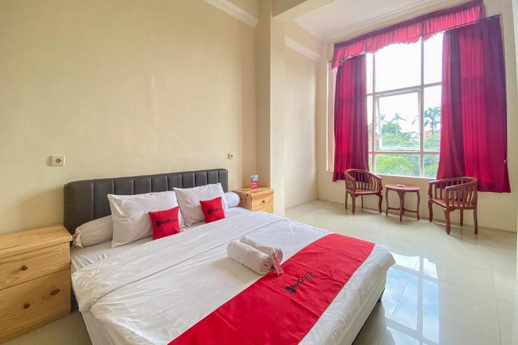 una camera da letto con un grande letto con accenti rossi di RedDoorz near Universitas Merdeka Malang 2 a Malang